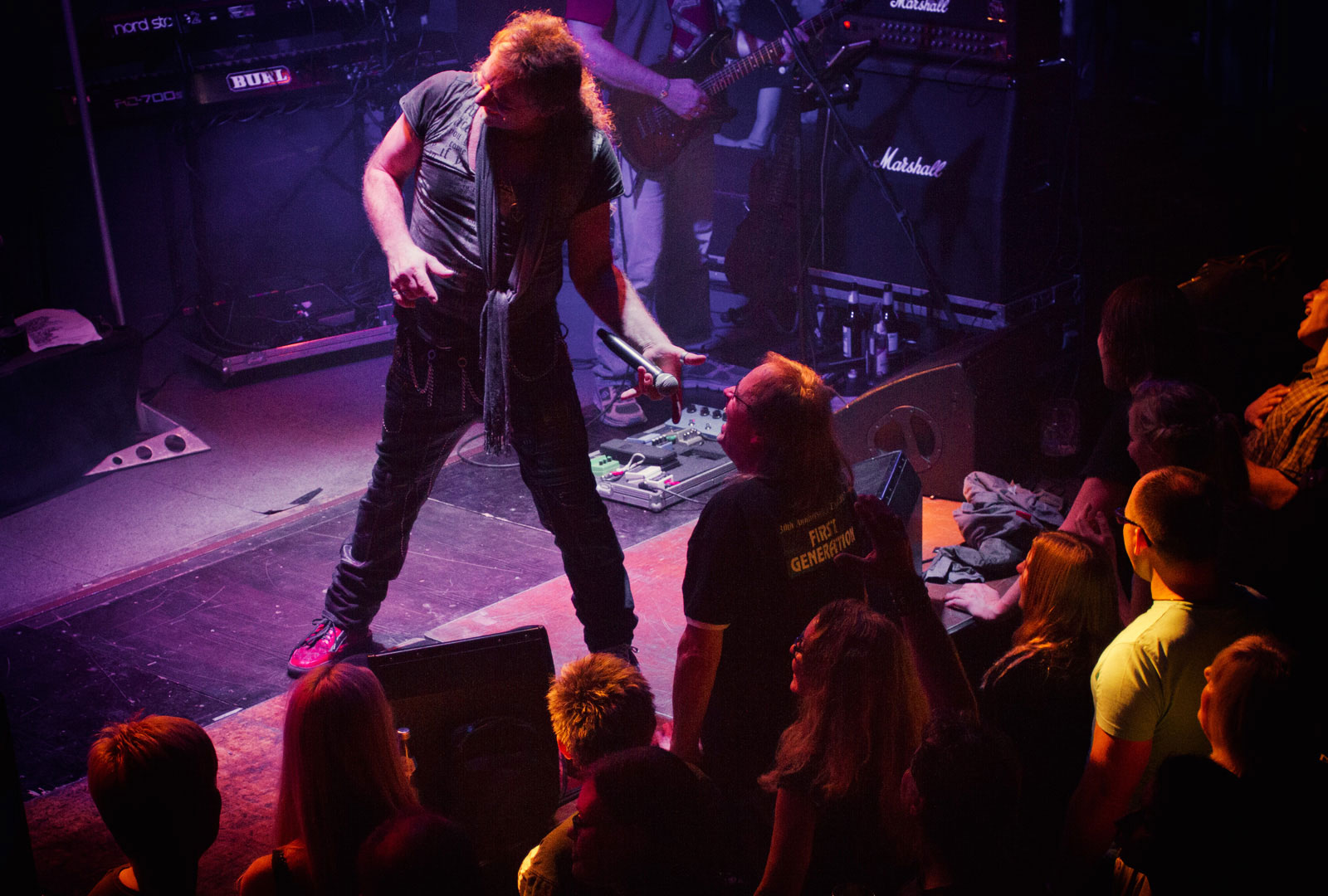 Sänger Martin Riegel hält einem männlichen Fan in der ersten Reihe sein Mikrofon hin.