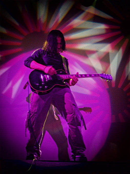 Gitarrist Sebastian Ostrowski mit Lightshow im Hintergrund
